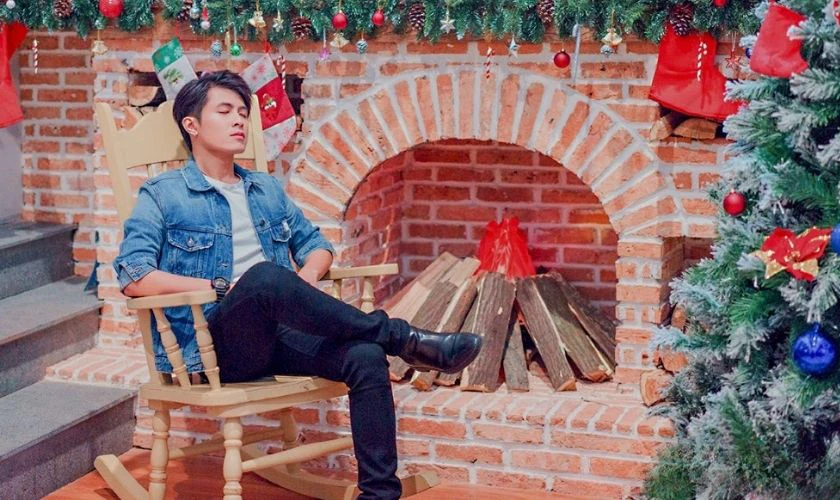 Chàng trai tạo dáng chụp ảnh Giáng sinh bên lò sưởi