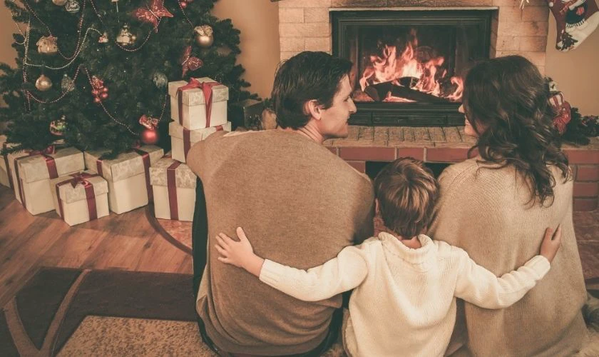 Gia đình tạo dáng chụp ảnh Noel bên lò sưởi