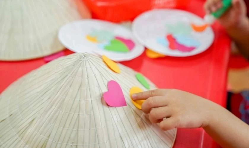 Dán giấy màu trái tim trang trí nón lá