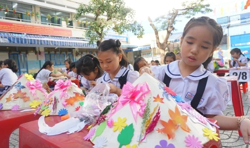Bé trang trí nón lá Tết với giấy màu